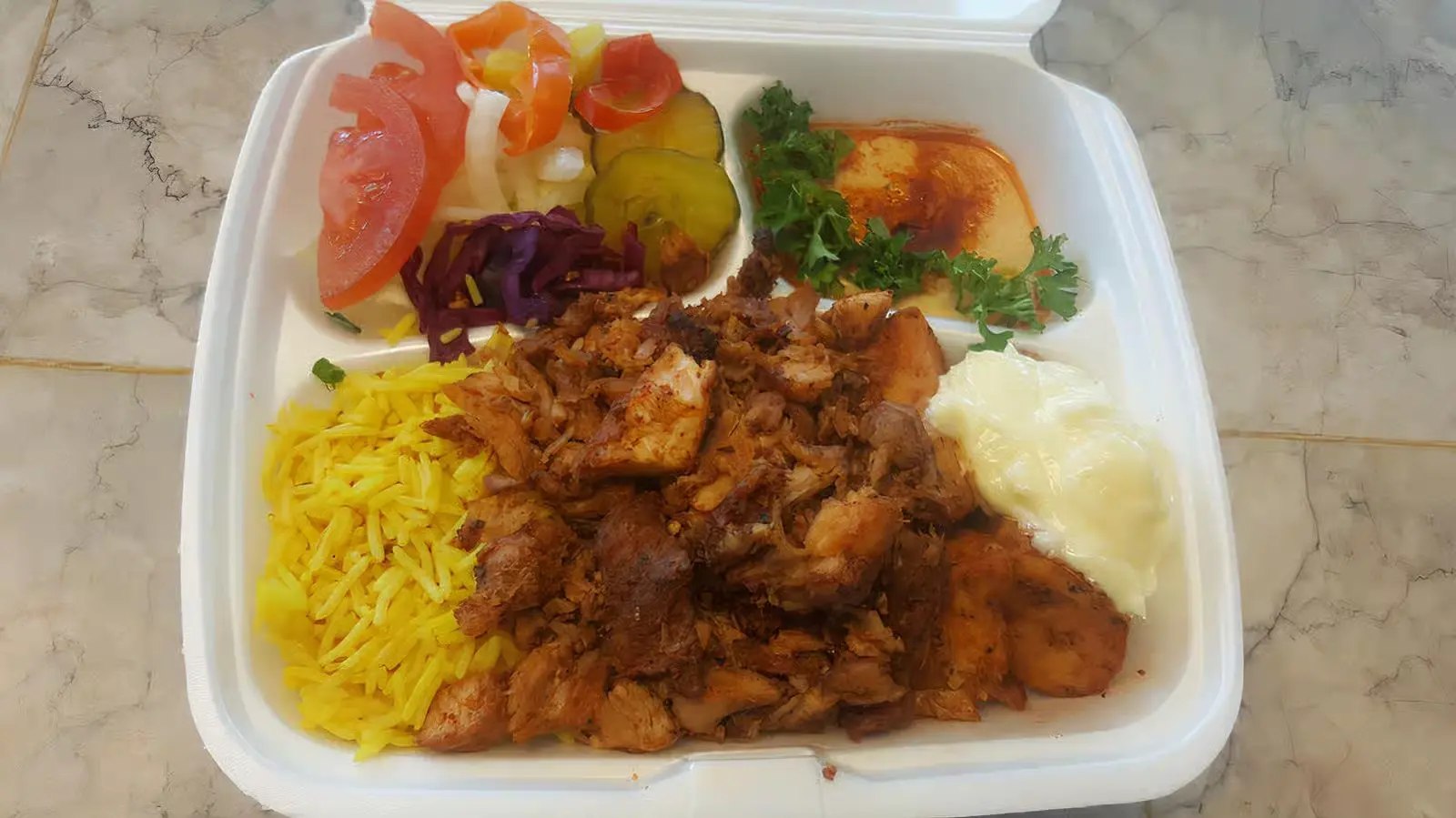 Chicken shawarma platter with seasoned rice, garlic sauce, hummus and fresh salad at King of Shawarma Calgary