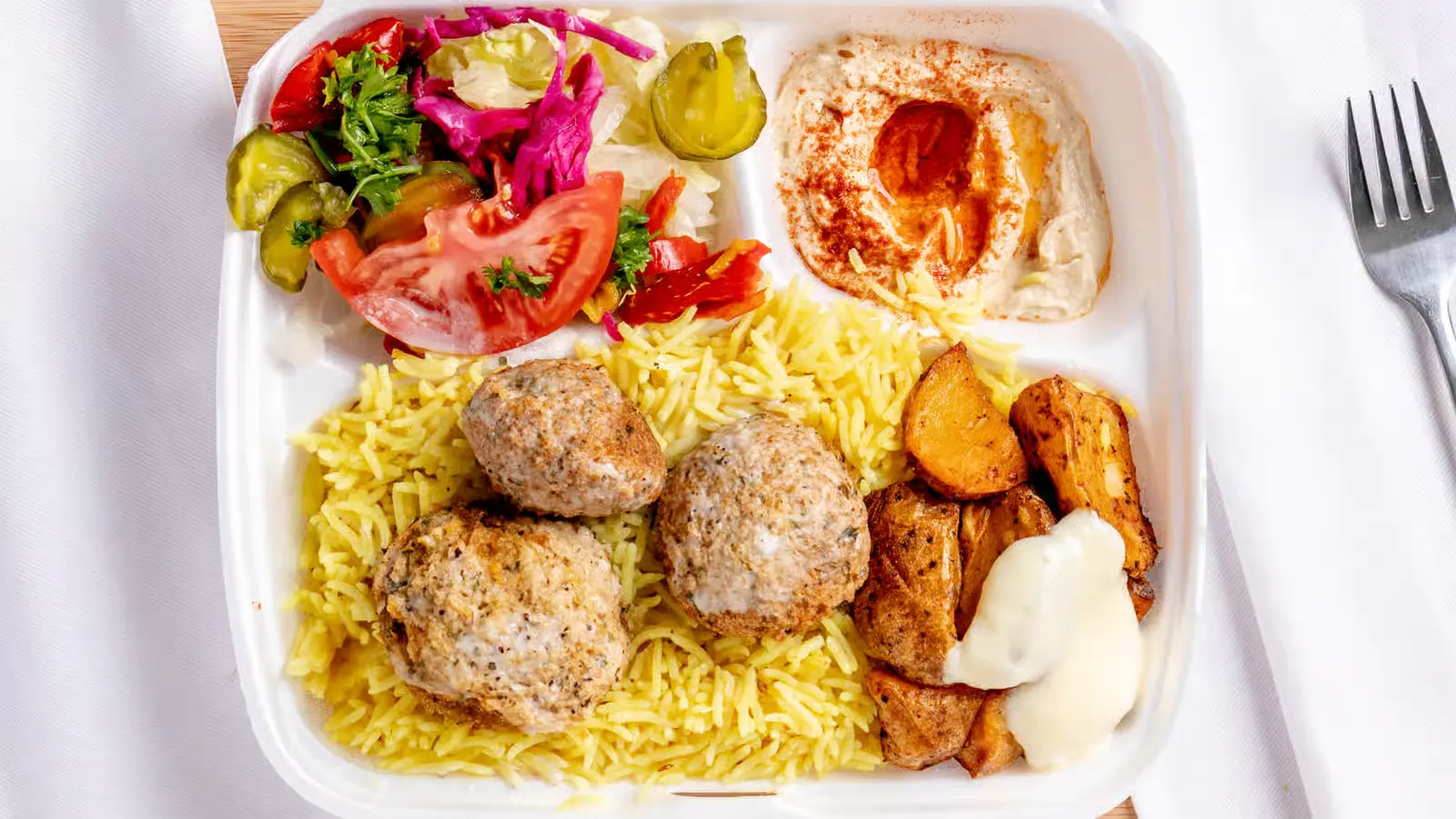 Kabob platter with seasoned rice, hummus, garlic potatoes and fresh salad at King of Shawarma Calgary